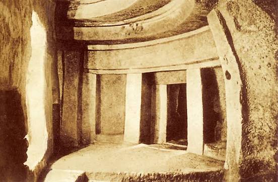 Early twentieth-century photograph of the carved limestone interior of the Ħal Saflieni Hypogeum, Malta, showing corbelled ceiling and columns